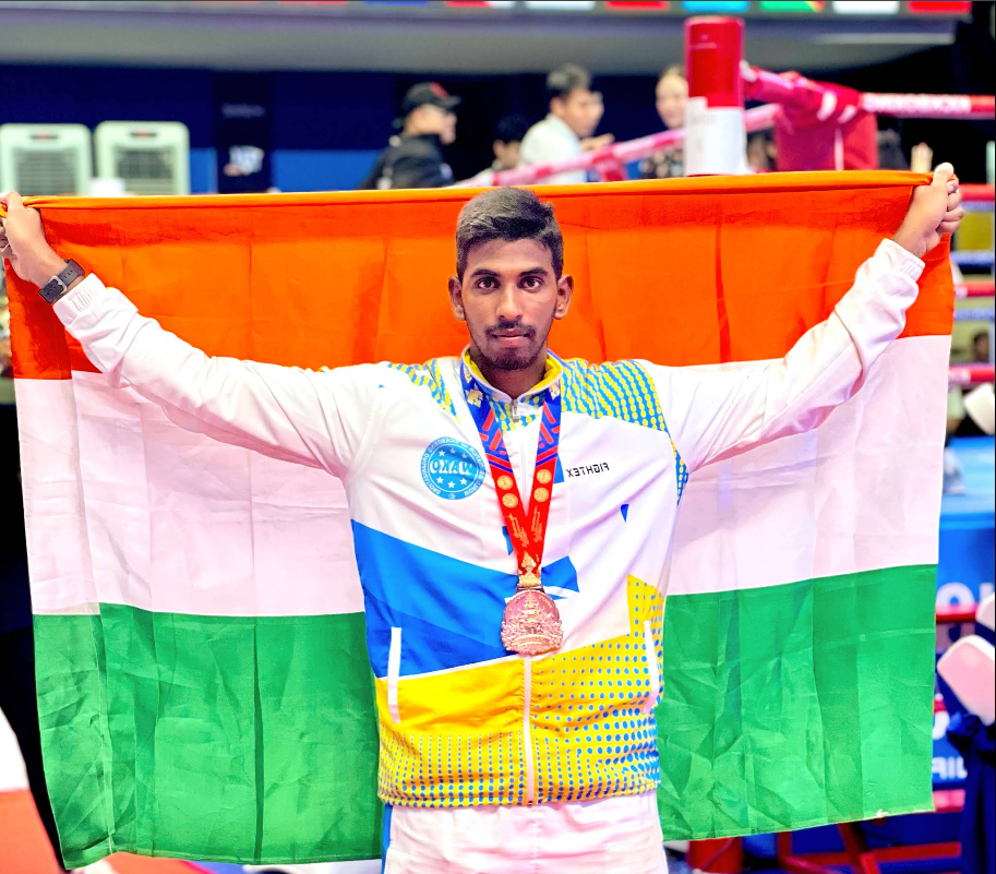 Coach Yasam Koti Naga Babu holding the Indian flag after a medal-winning bout